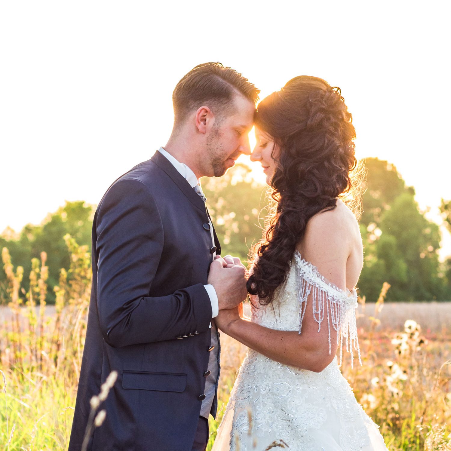 frisch verheiratetes Paerchen im Hochzeitsoutfit im Feld im rahmen eines after wedding fotoshootings